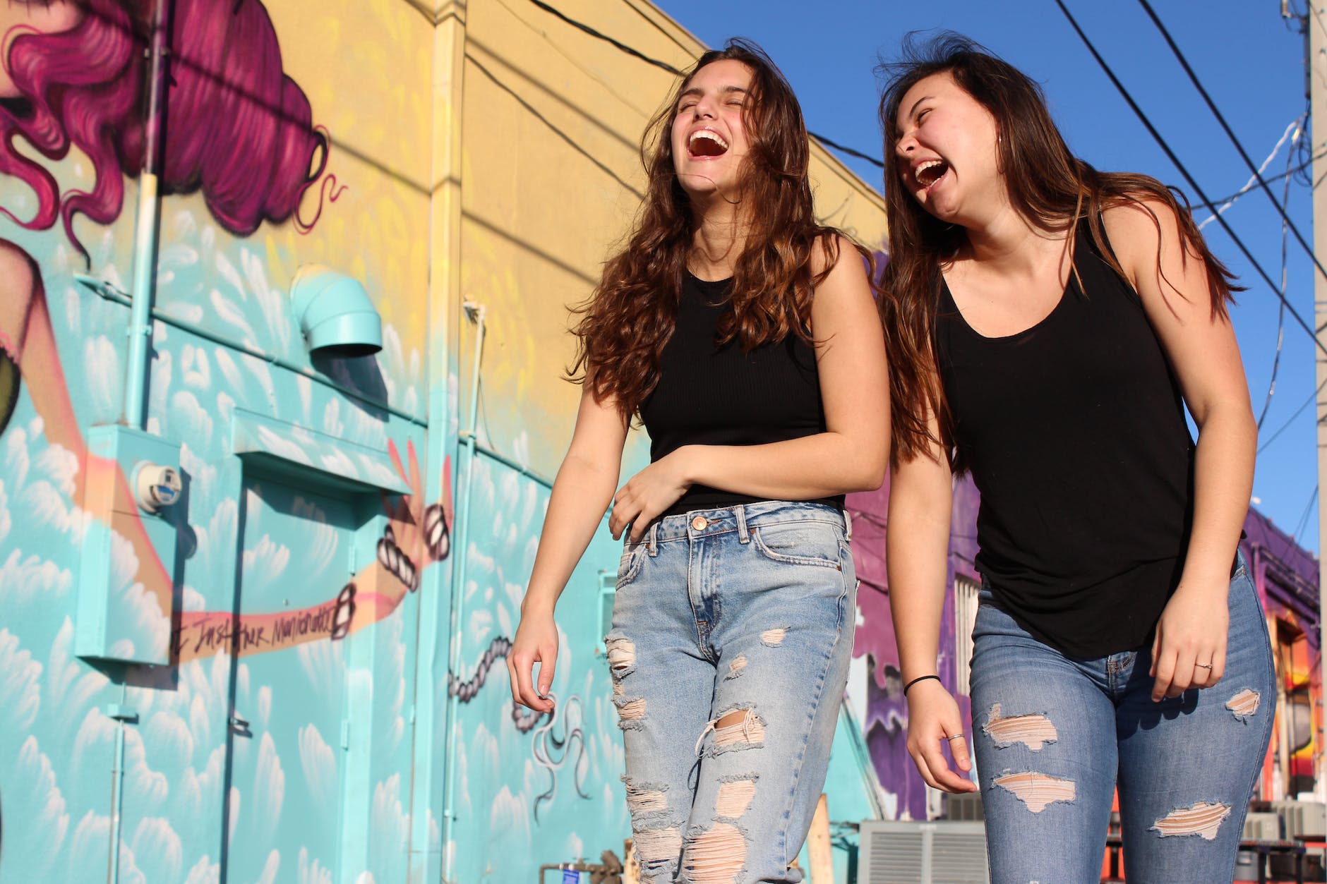 photo of two laughing women walking past graffiti wall
